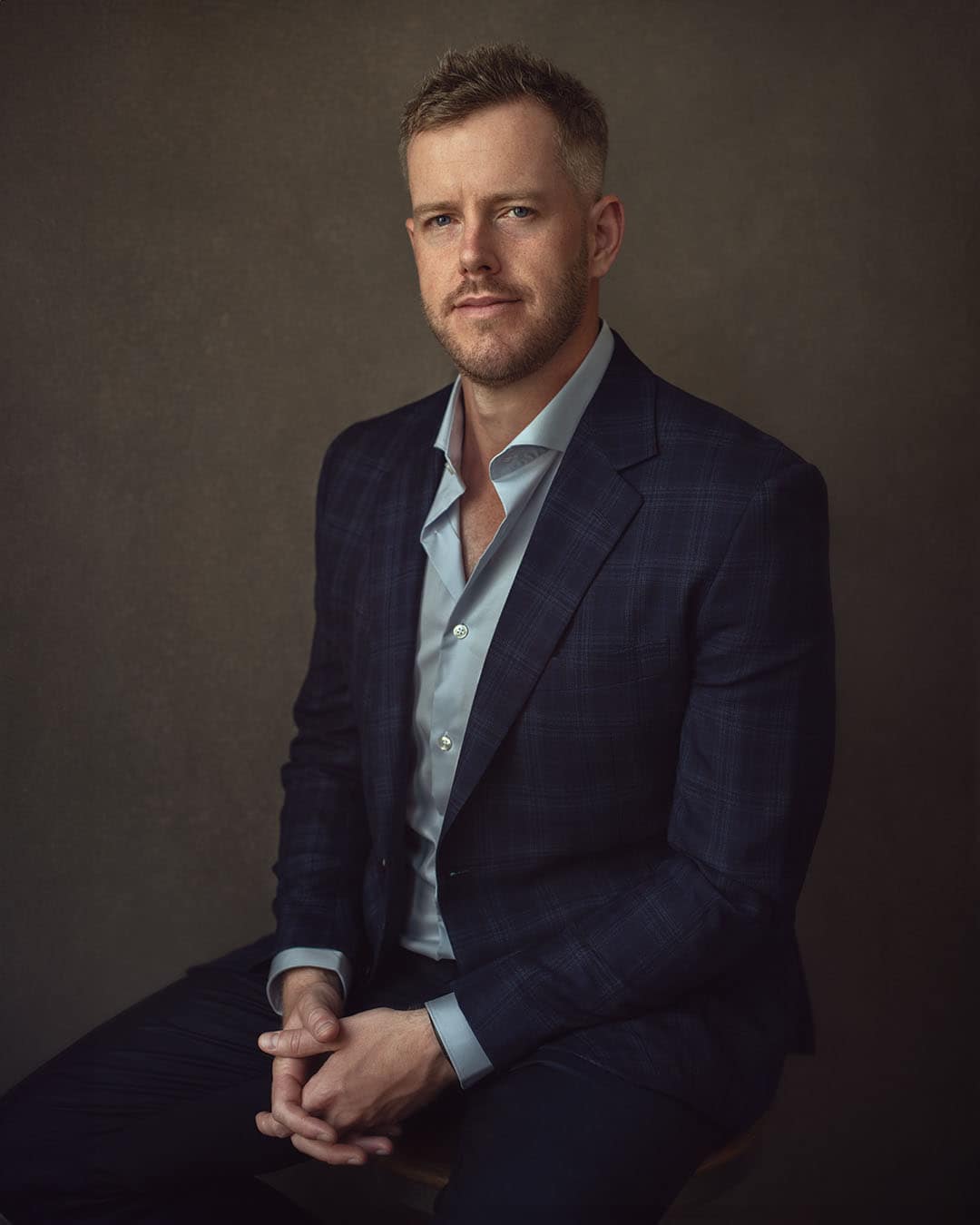 Seated male executive in navy blazer with soft lighting, corporate portrait in Dubai