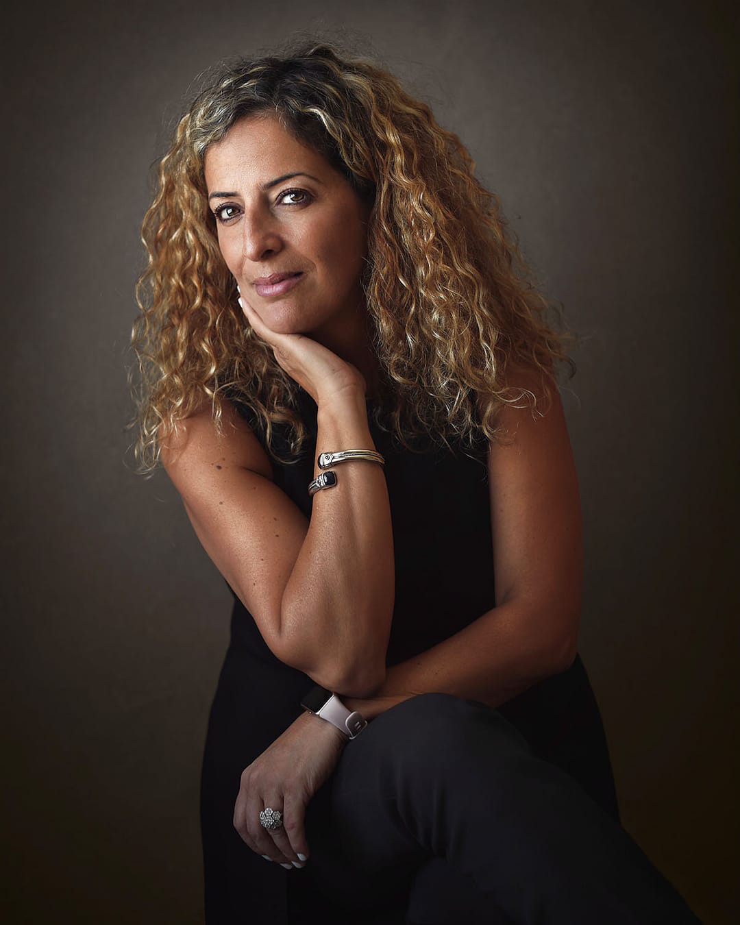 Confident woman with curly hair in fine art corporate headshot, photographed in Dubai studio