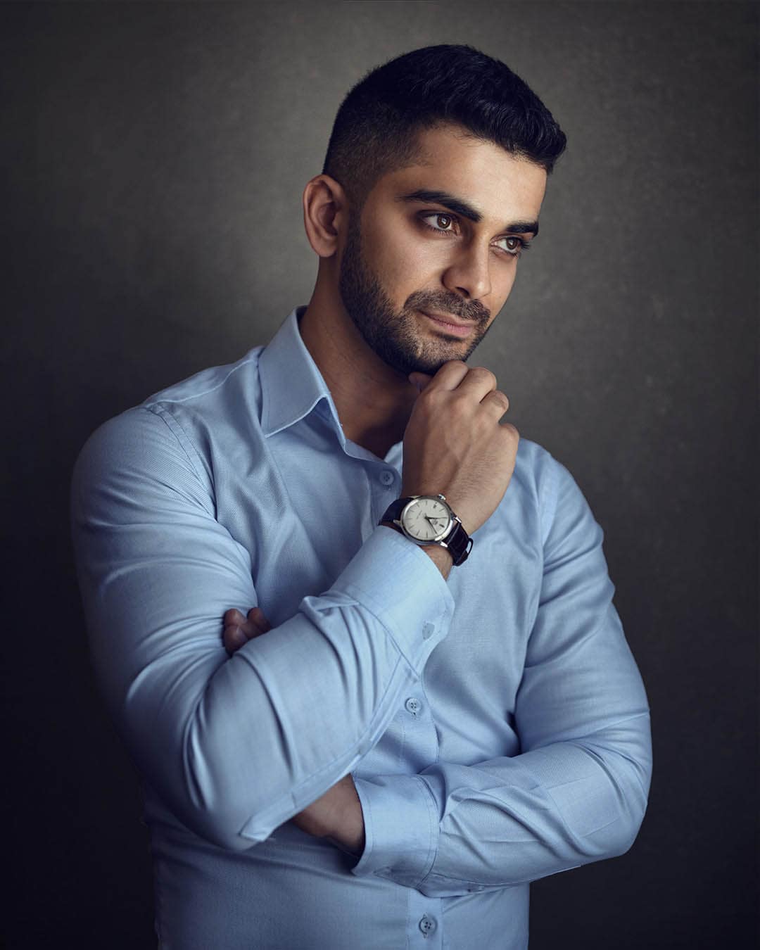 Male business headshot in light blue shirt, arms folded, Dubai studio