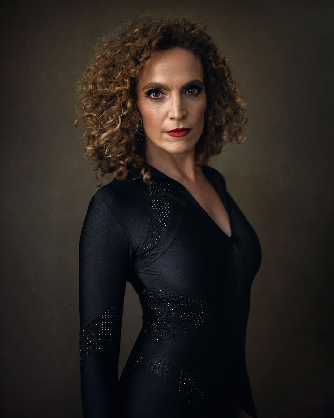 Confident female corporate headshot in black outfit, photographed in Dubai with fine art lighting