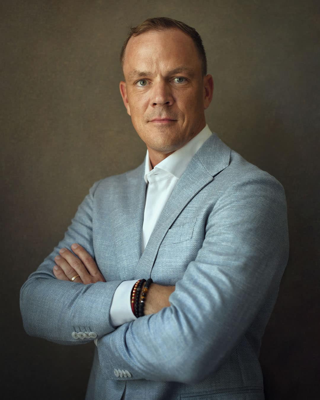 Executive LinkedIn headshot in Dubai photographed in a fine art portrait style with natural window light and professional business attire.