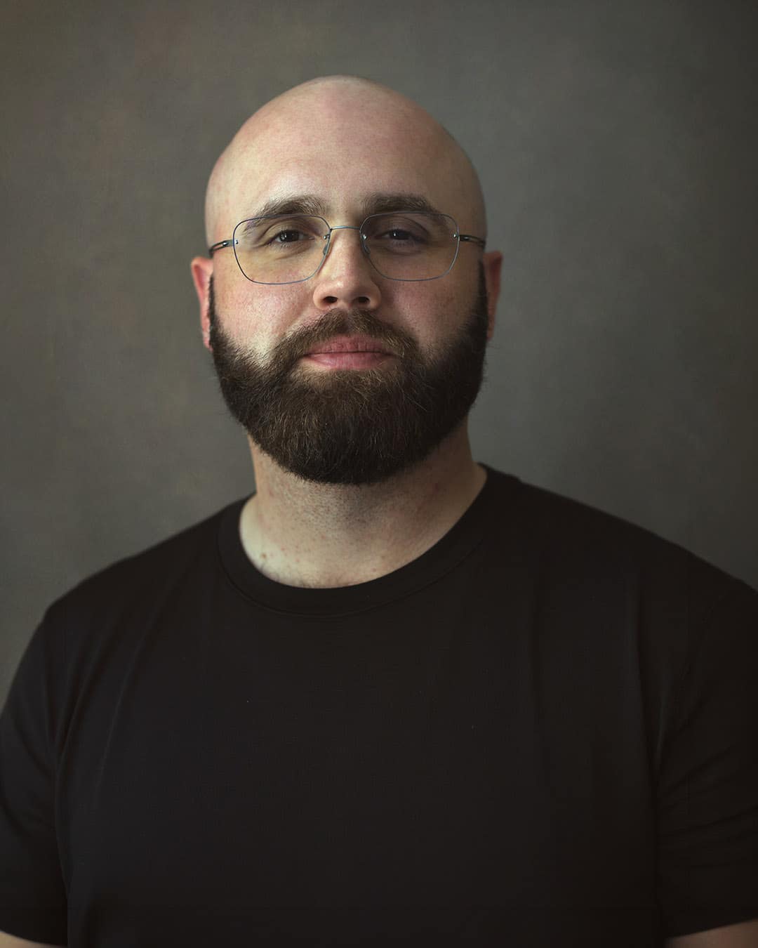 Professional headshot in Dubai of a man wearing a plain black T-shirt, showing how solid colours keep the face as the focal point.