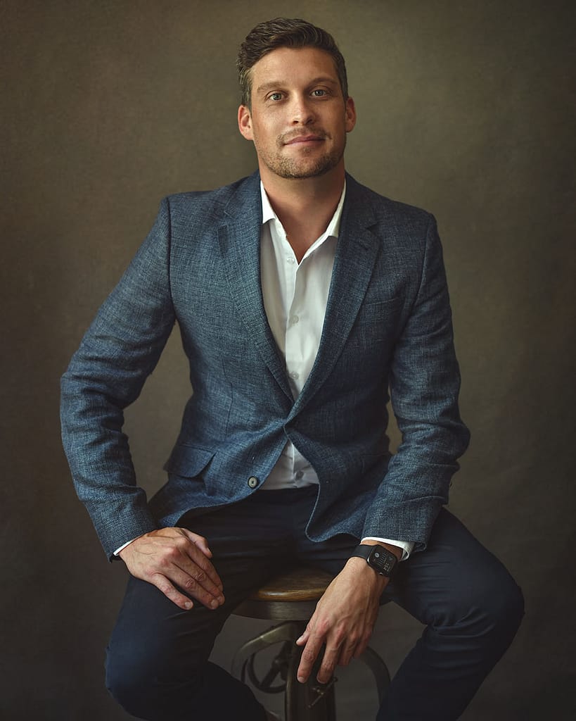Seated male executive portrait in blue suit by Dubai portrait photographer for professionals