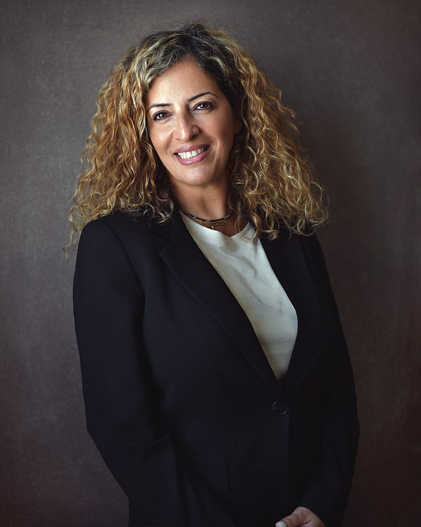 Corporate portrait photography example: mid-aged business woman smiling at the camera in a black jacket.