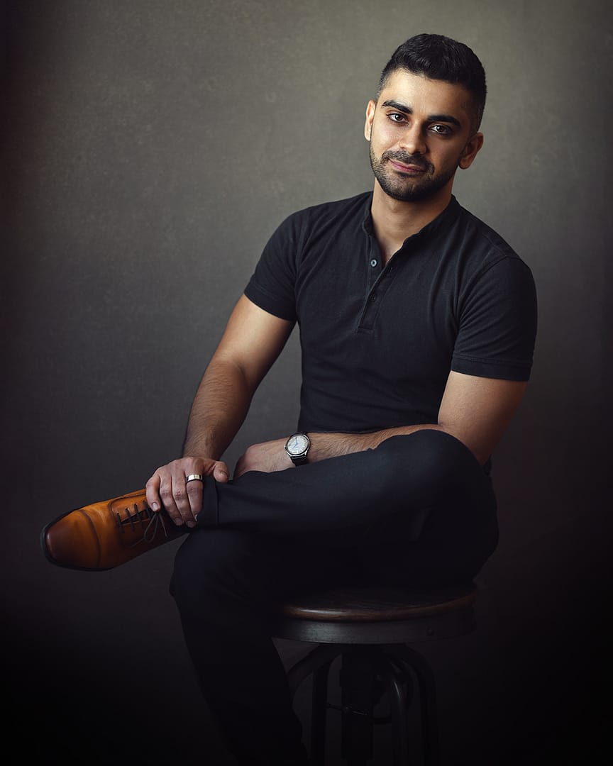 Dubai portrait of a young professional in fine art style, sitting confidently with one leg crossed over.