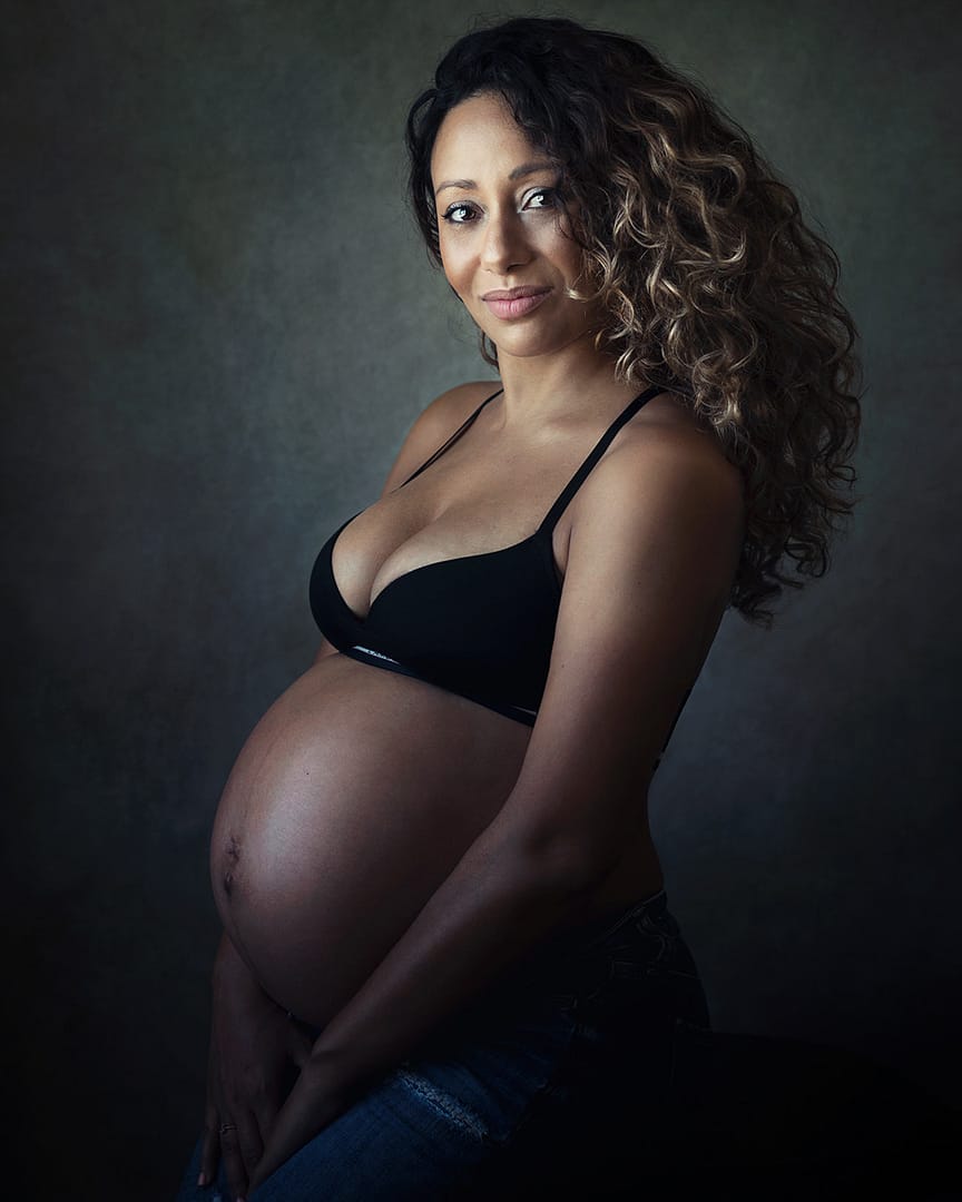 Maternity photo of pregnant woman in black bra seated on chair in Dubai.